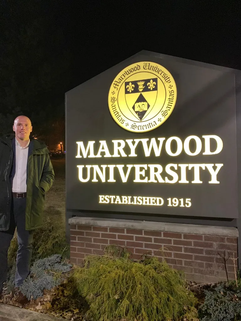 Marywood Criminal Justice Fulbright Lecturer in front of the Marywood Sign outside of the Nazareth Center